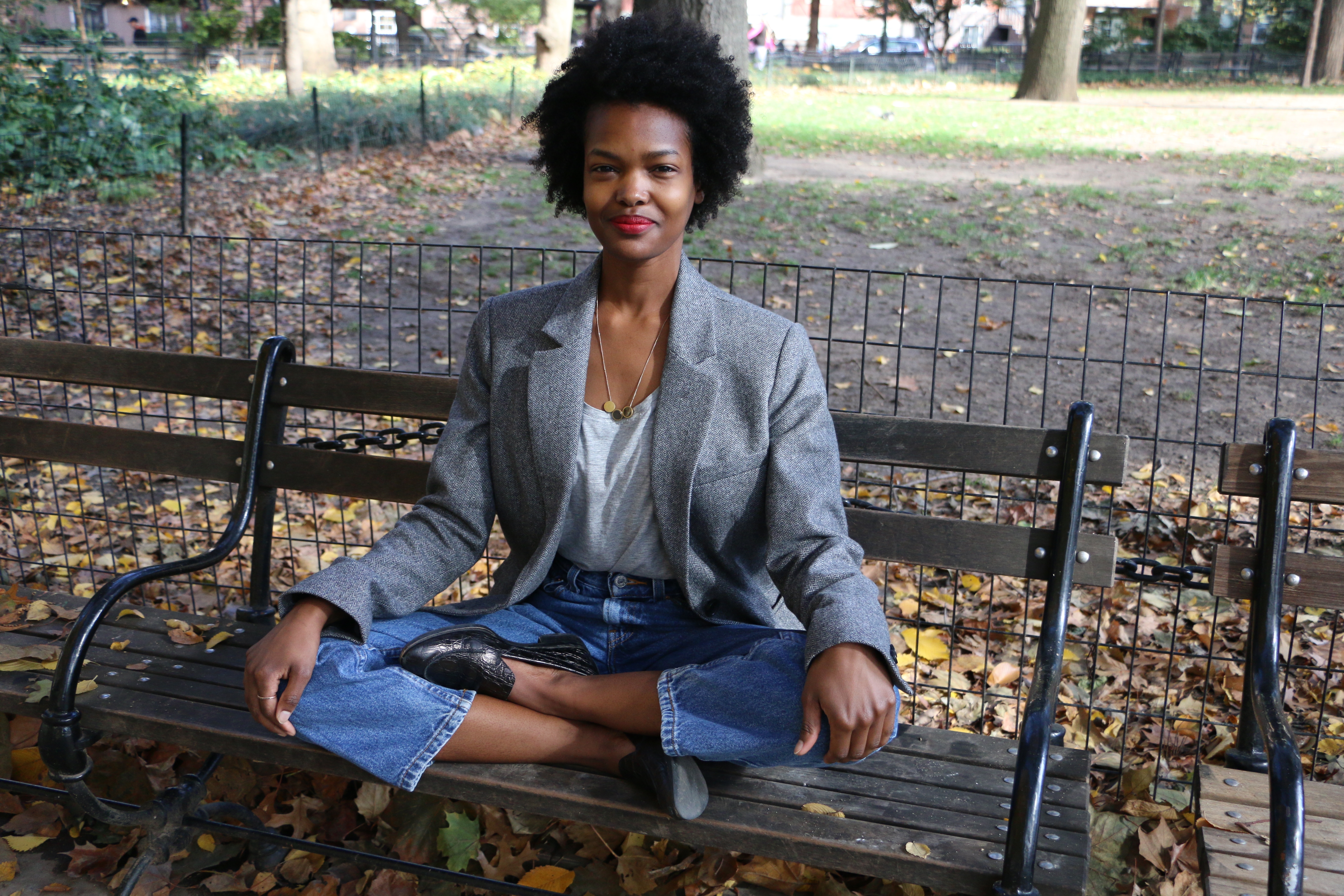 Jessica Angima sitting cross legged on a bench